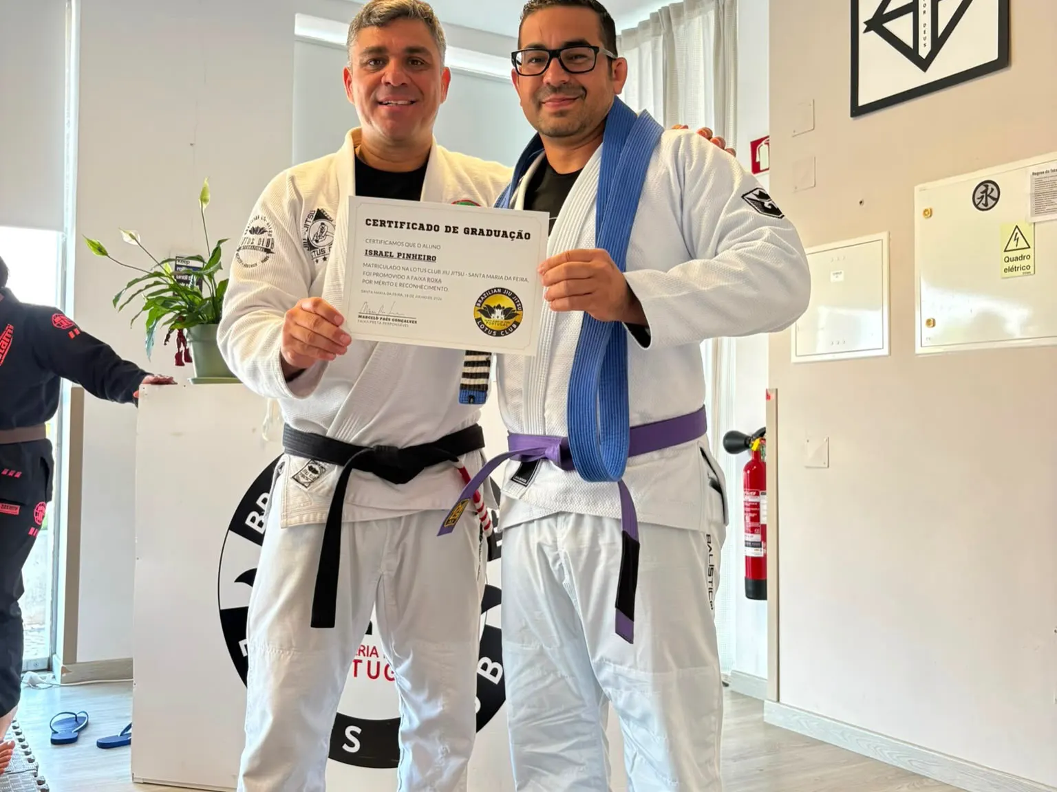 Professor e aluno com o certificado de graduação para faixa roxa