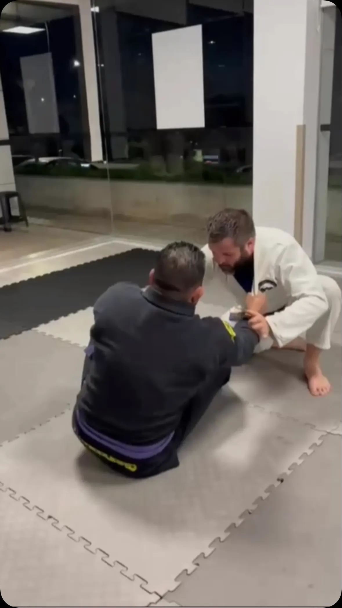 Dois alunos a treinar no chão, um sentado na guarda